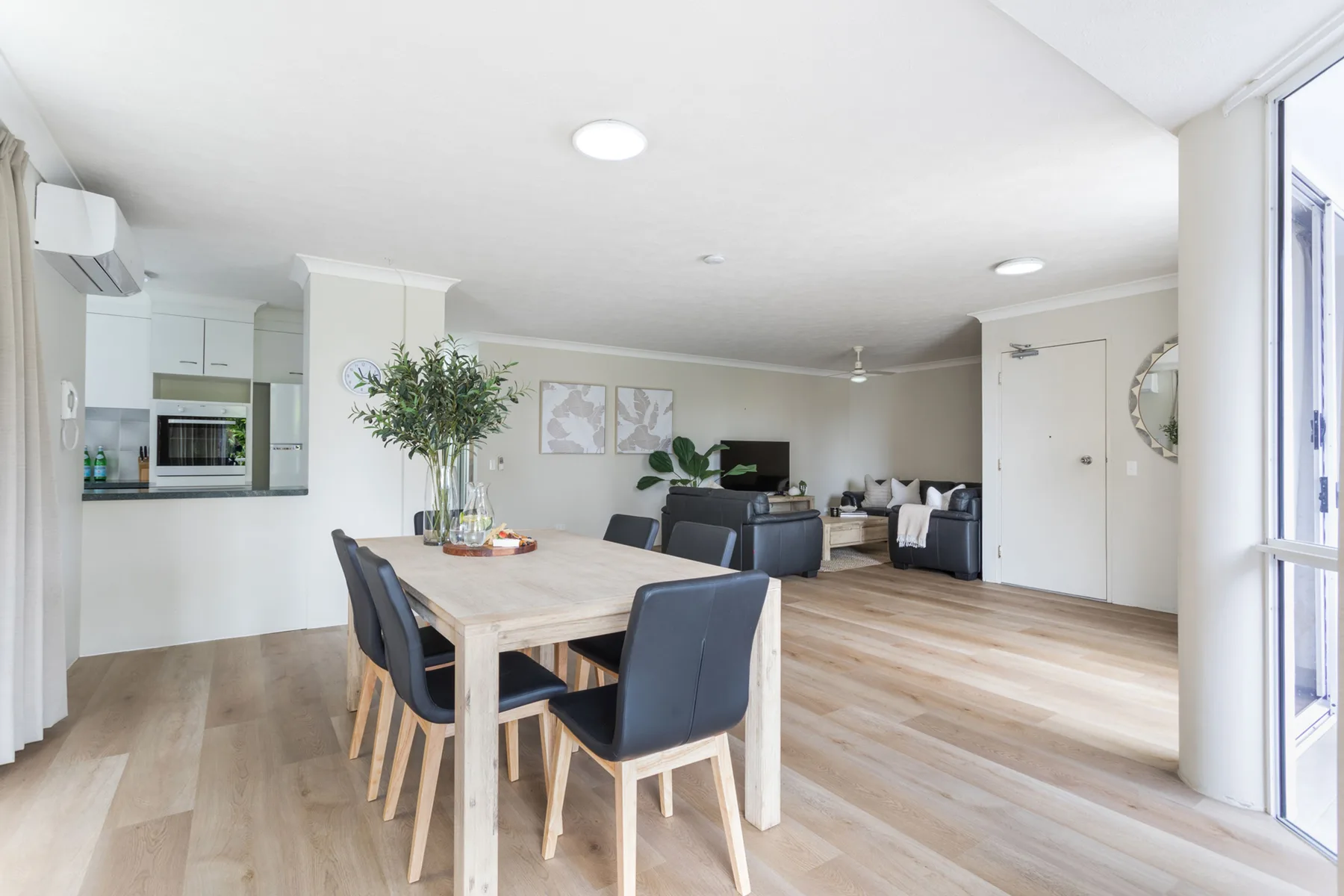 Sala y comedor de concepto abierto con una mesa de madera clara y asientos oscuros.