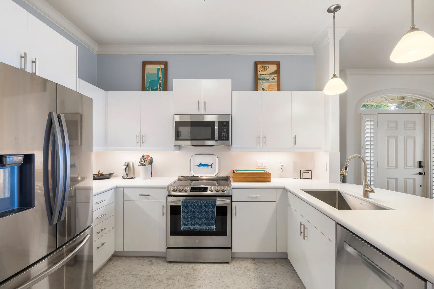 A bright kitchen with white cabinets, stainless steel appliances, and a central cooking area.