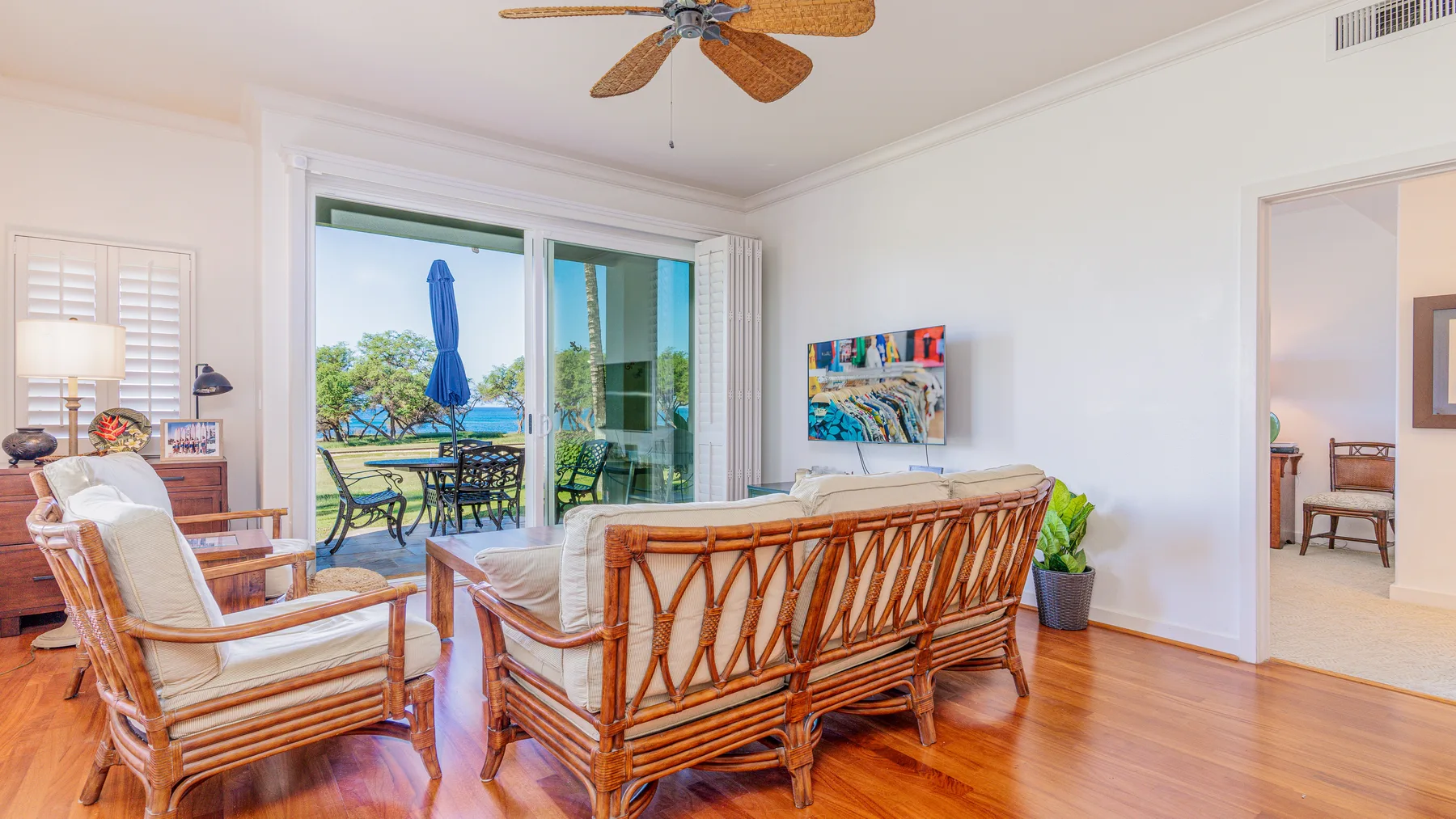 A bright living room with rattan seating and sliding glass doors opening to a patio.