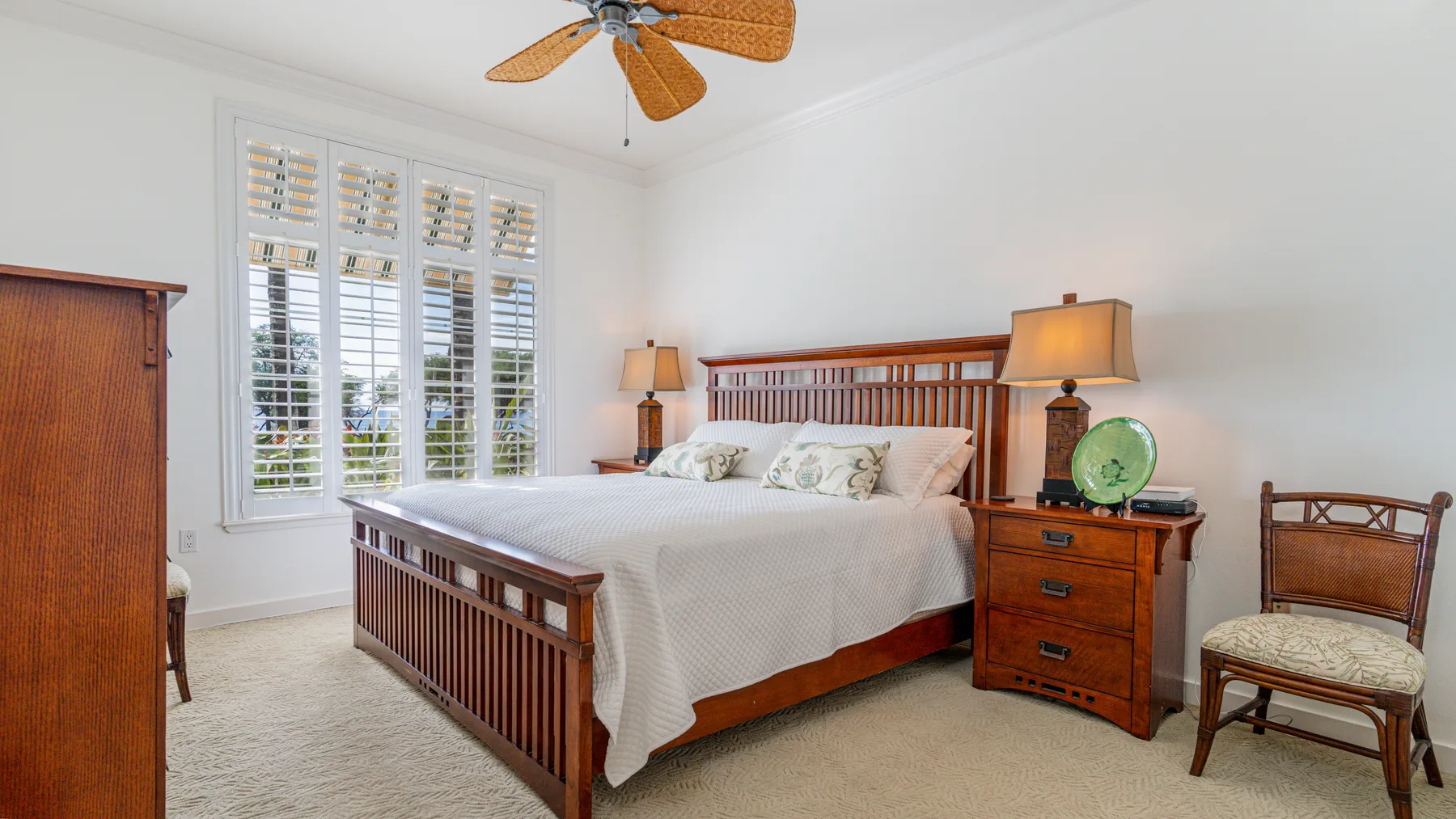 A bedroom with a wooden bed, white bedding, and shuttered windows.