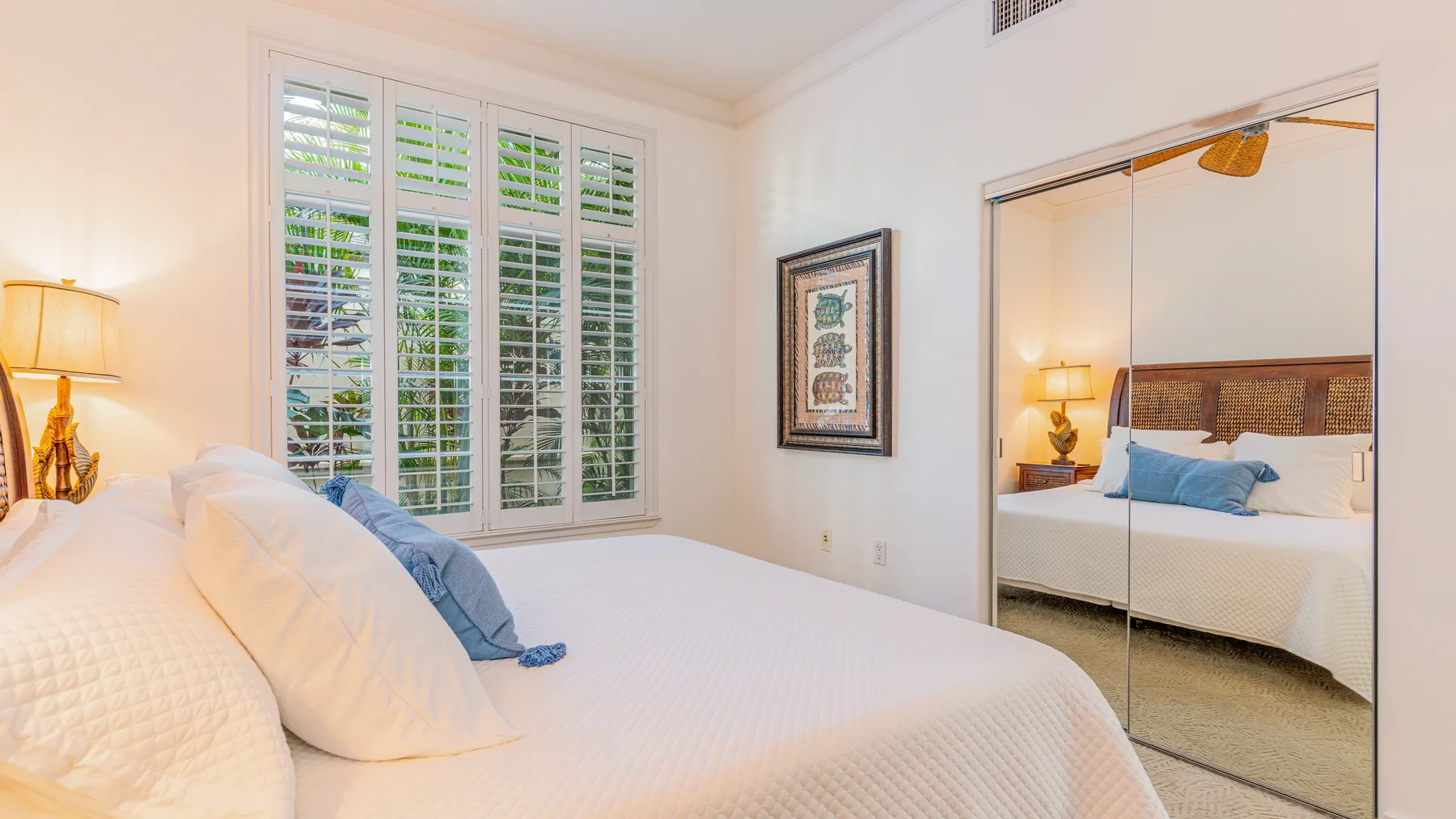 A bright bedroom with a large bed and tall shuttered windows.