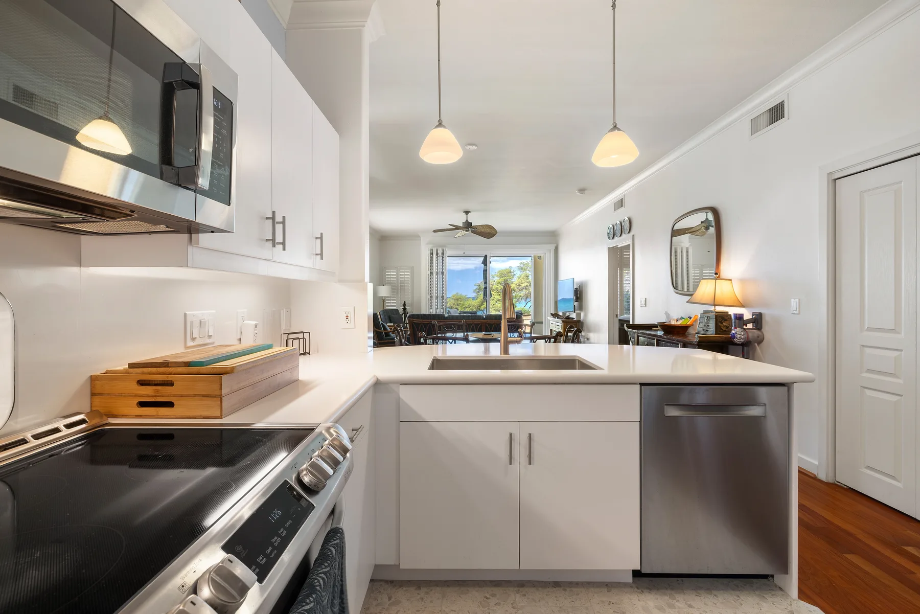 A bright kitchen with white cabinets, a cooktop, and a sink.