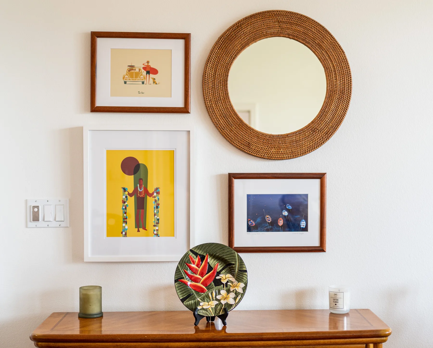 A wooden console table sits beneath framed artwork and a round wall mirror.