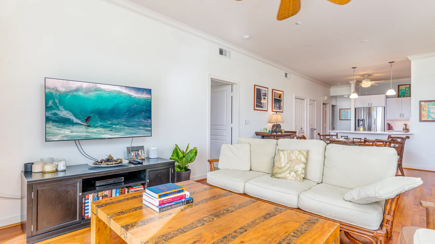 A living room with a white sofa, wooden coffee table, and television.