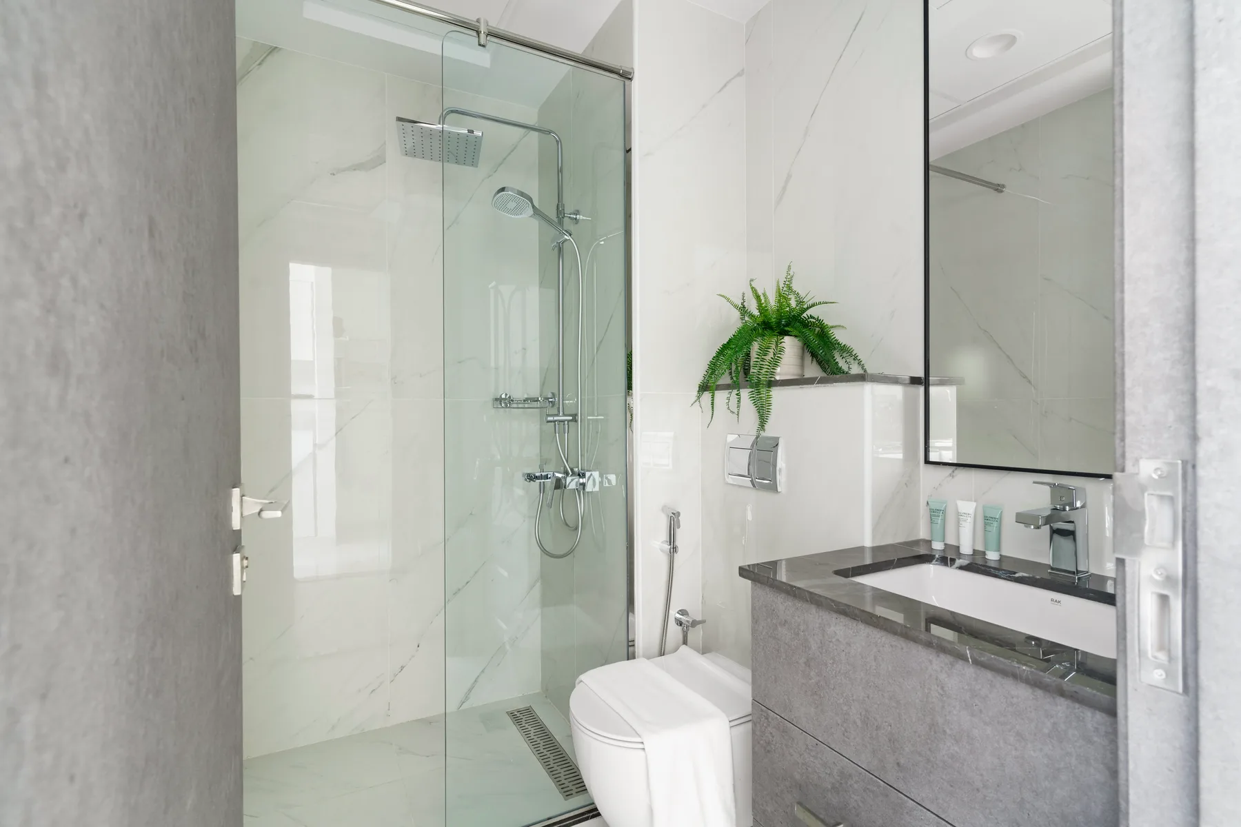 Un baño luminoso con ducha de vidrio y lavabo.