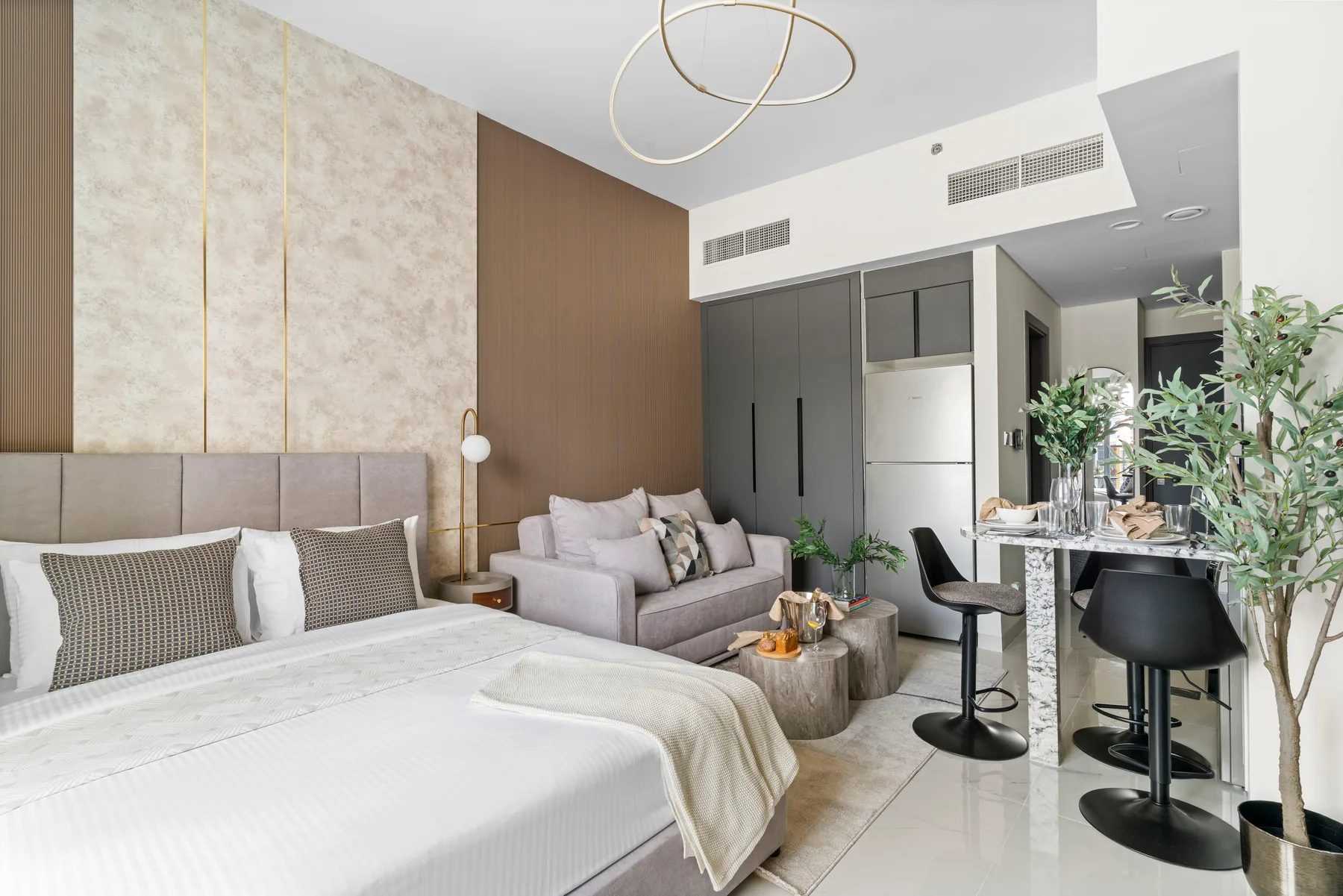 Dormitorio con cama, zona de estar y una pequeña cocina al fondo.