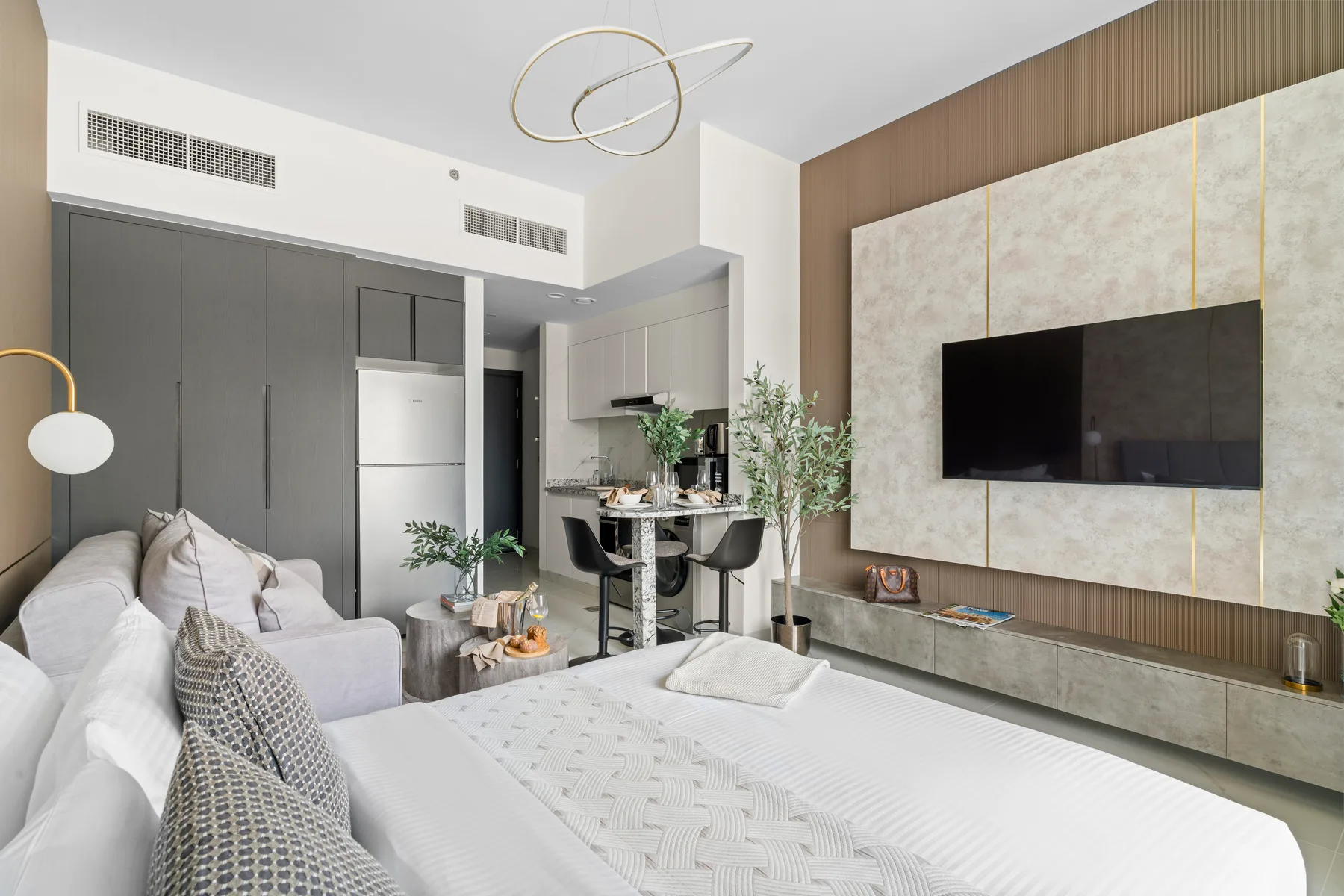 Dormitorio moderno con una cama grande, zona de estar y televisor en la pared.
