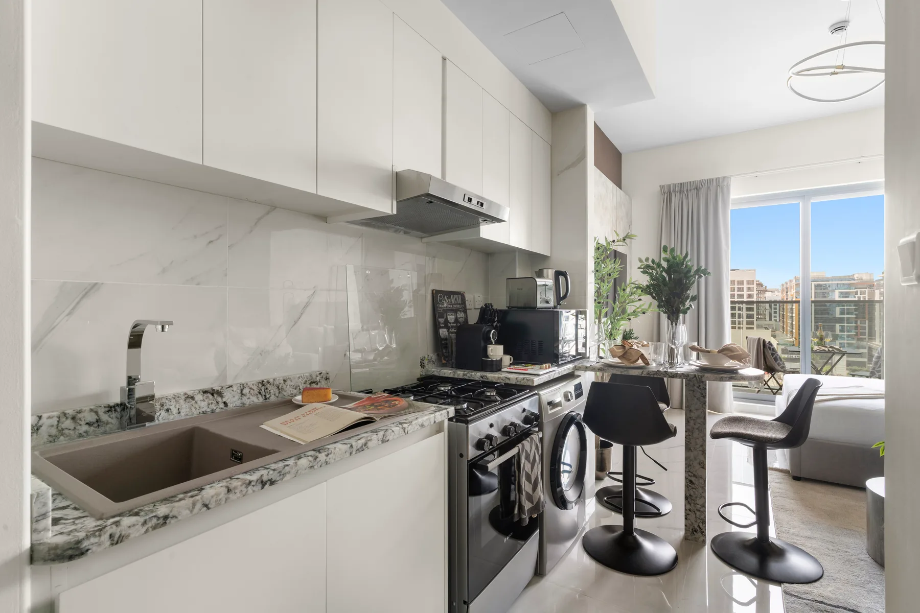 Una cocina luminosa con comedor se abre a un balcón a través de grandes ventanales.