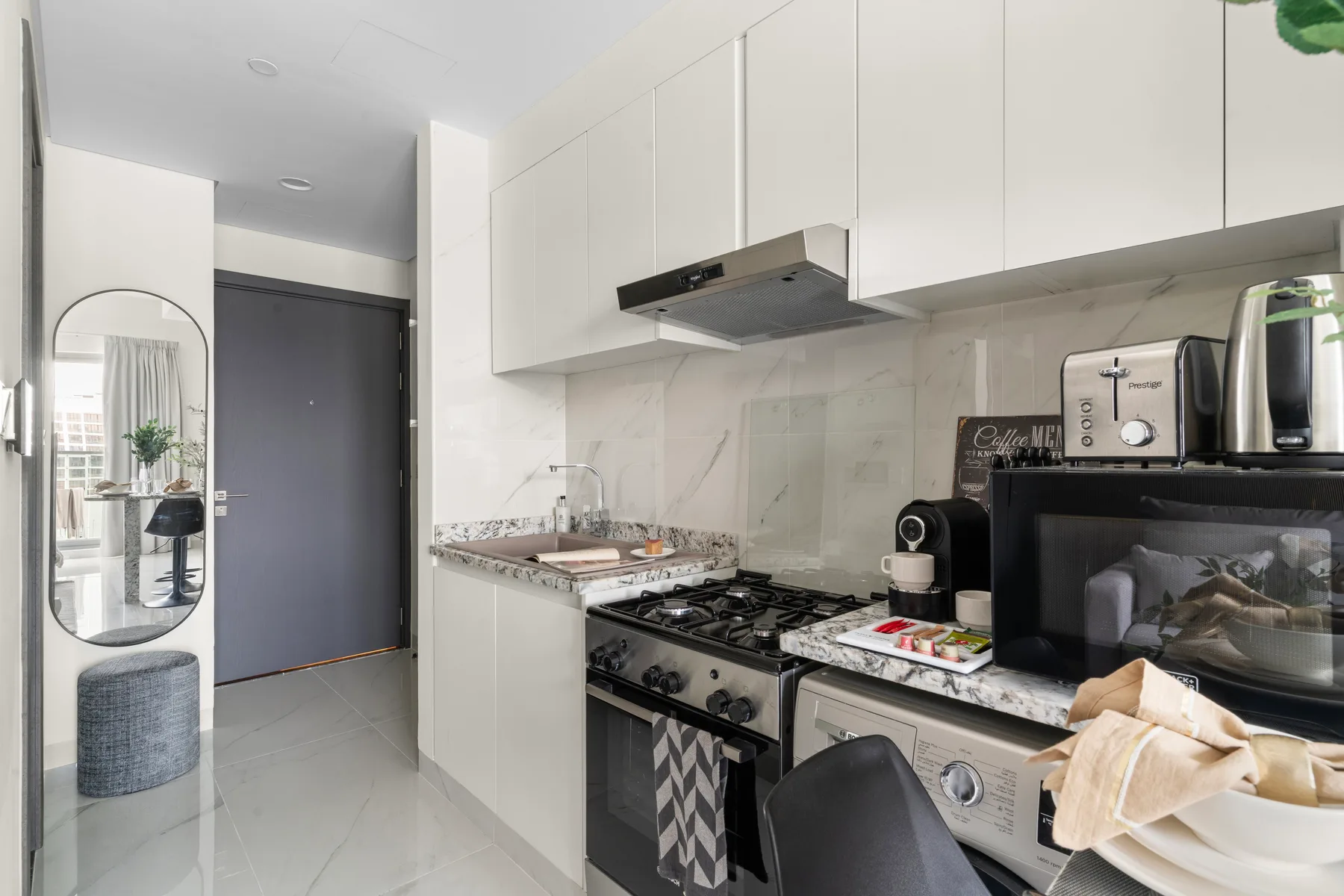 Una cocina compacta con gabinetes blancos, una encimera y electrodomésticos.