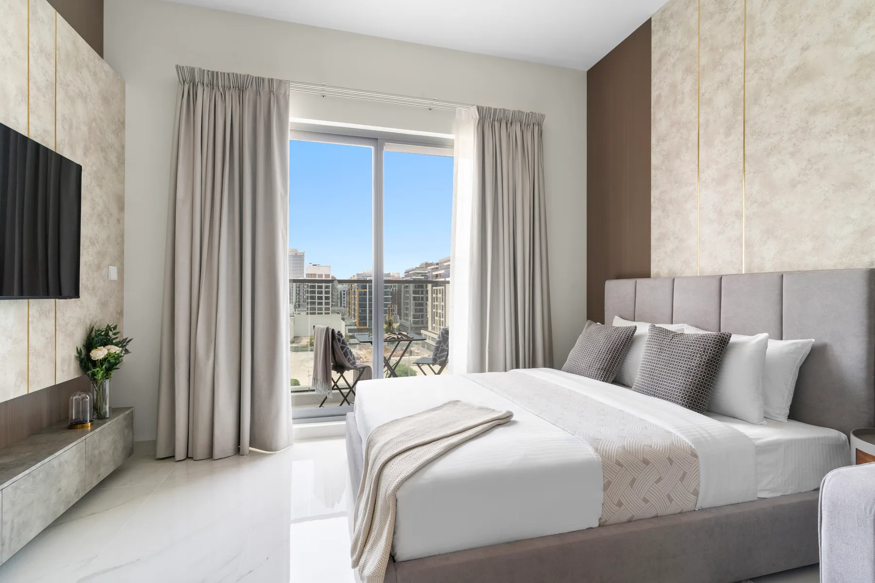 Un dormitorio luminoso con una cama grande junto a una ventana con cortinas.