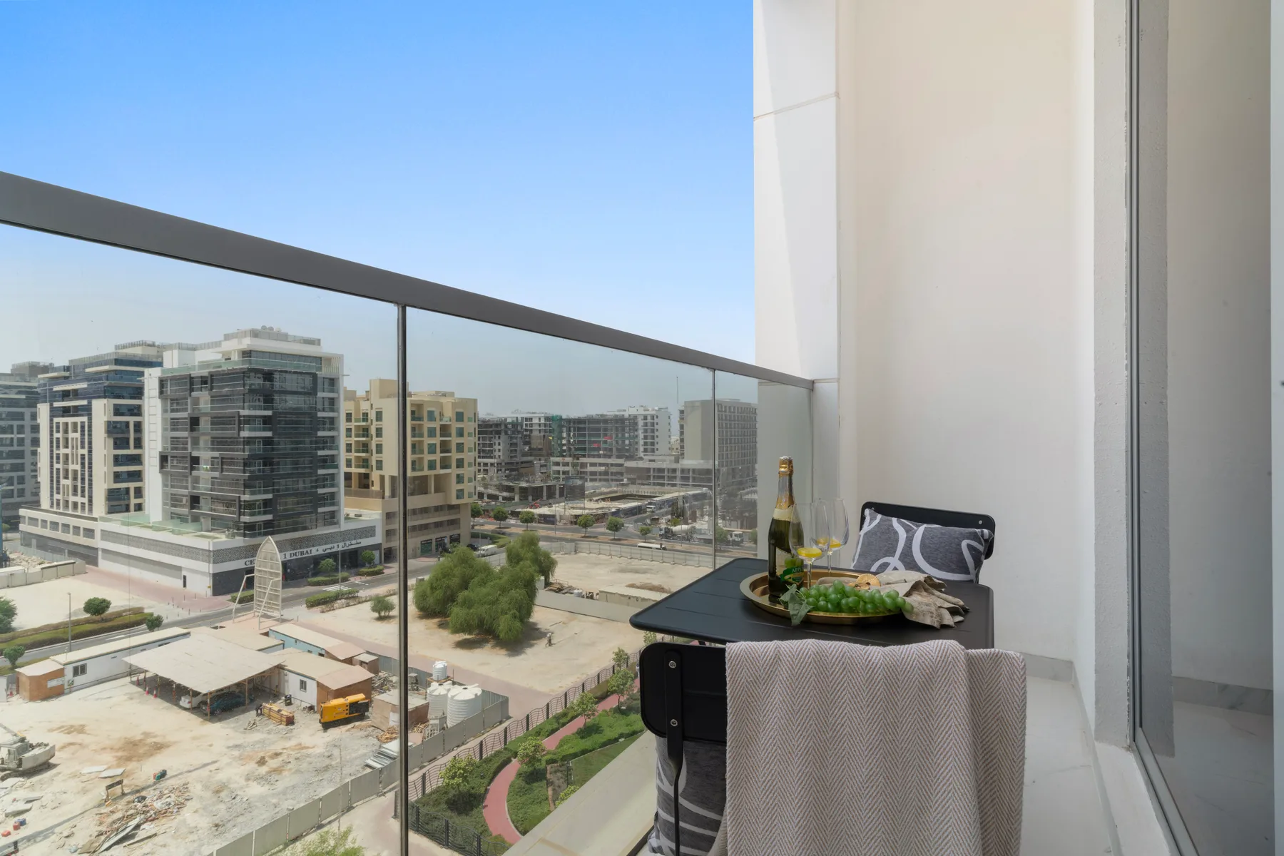 Una zona de estar en el balcón tiene vistas a edificios modernos y jardines.