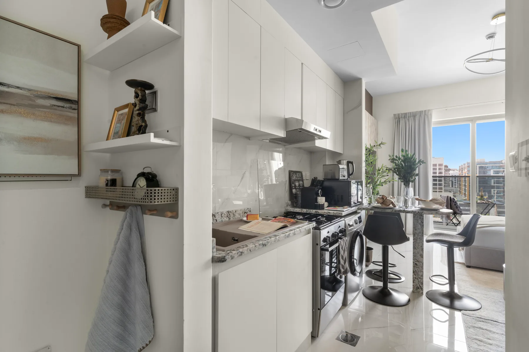Una cocina moderna se abre a un comedor junto a grandes ventanales.