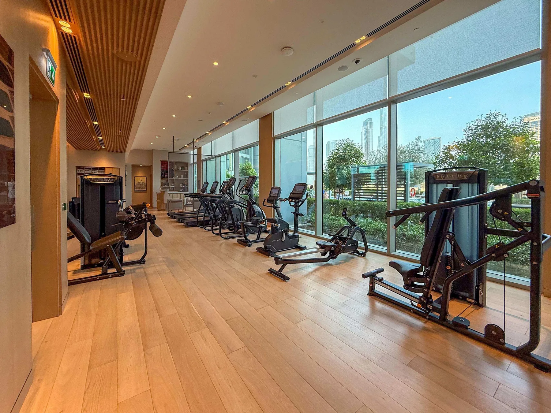 Una sala de fitness con máquinas de ejercicio junto a ventanales.