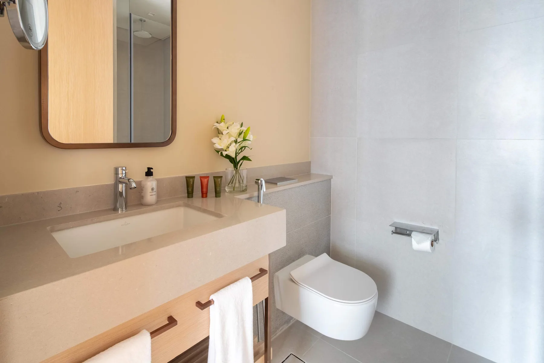Un baño luminoso con un lavabo amplio, un inodoro suspendido y un espejo.