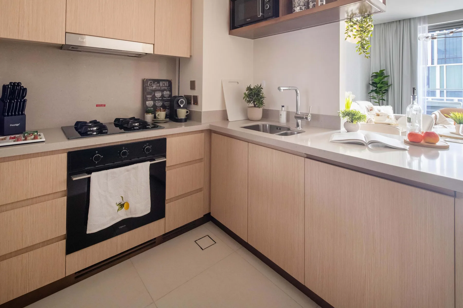 Una cocina moderna con gabinetes de madera clara, una estufa y un fregadero.