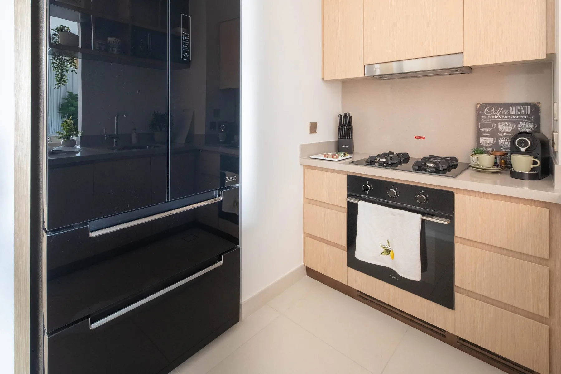 Una cocina moderna con refrigerador negro, placa de cocina y horno empotrado.