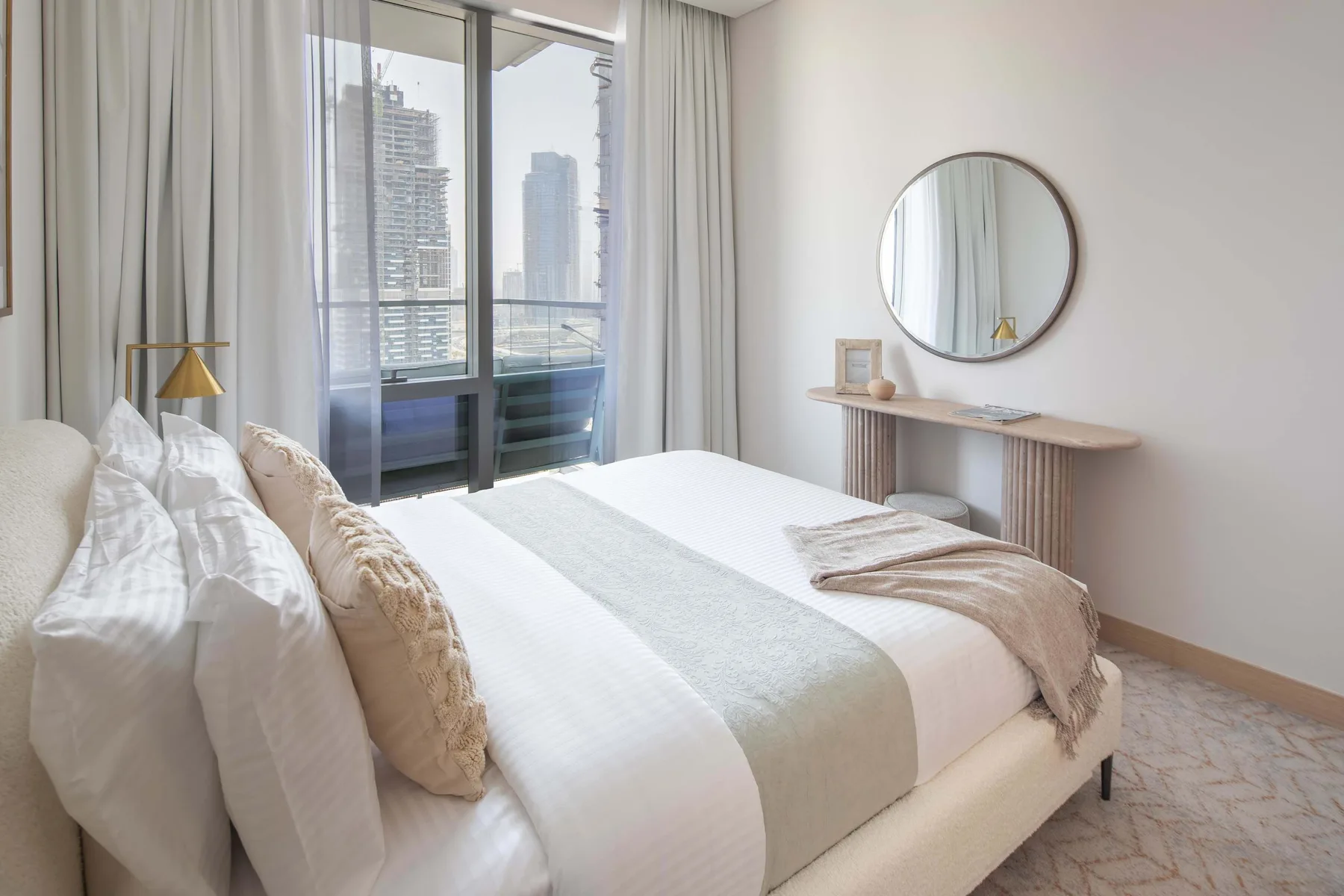 Un dormitorio luminoso con una cama bien hecha junto a una ventana grande.