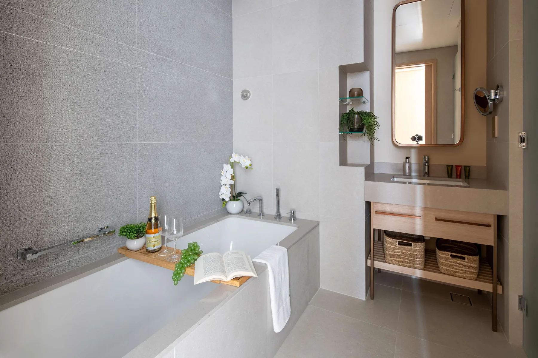 Un baño con bañera, tocador y espejo de pared.