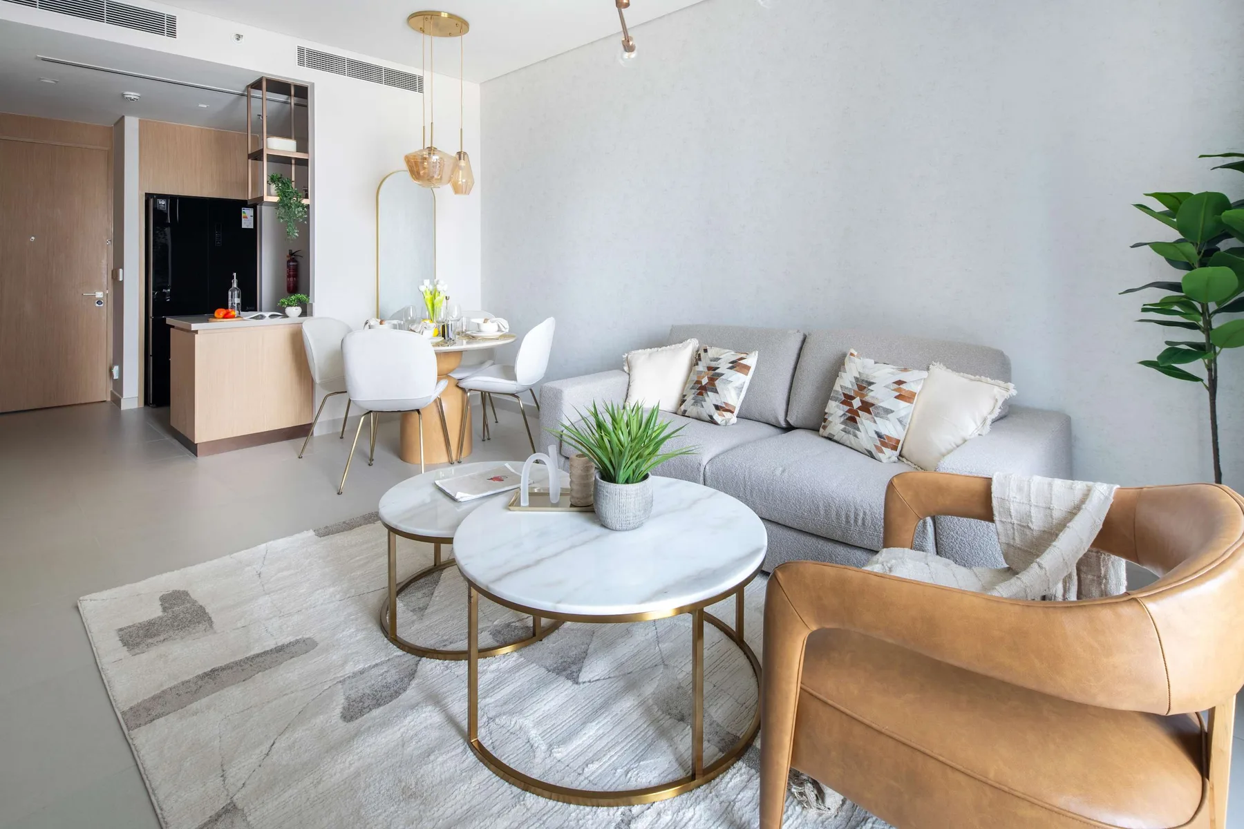 Una sala de estar luminosa con un sofá gris y una mesa de centro redonda.
