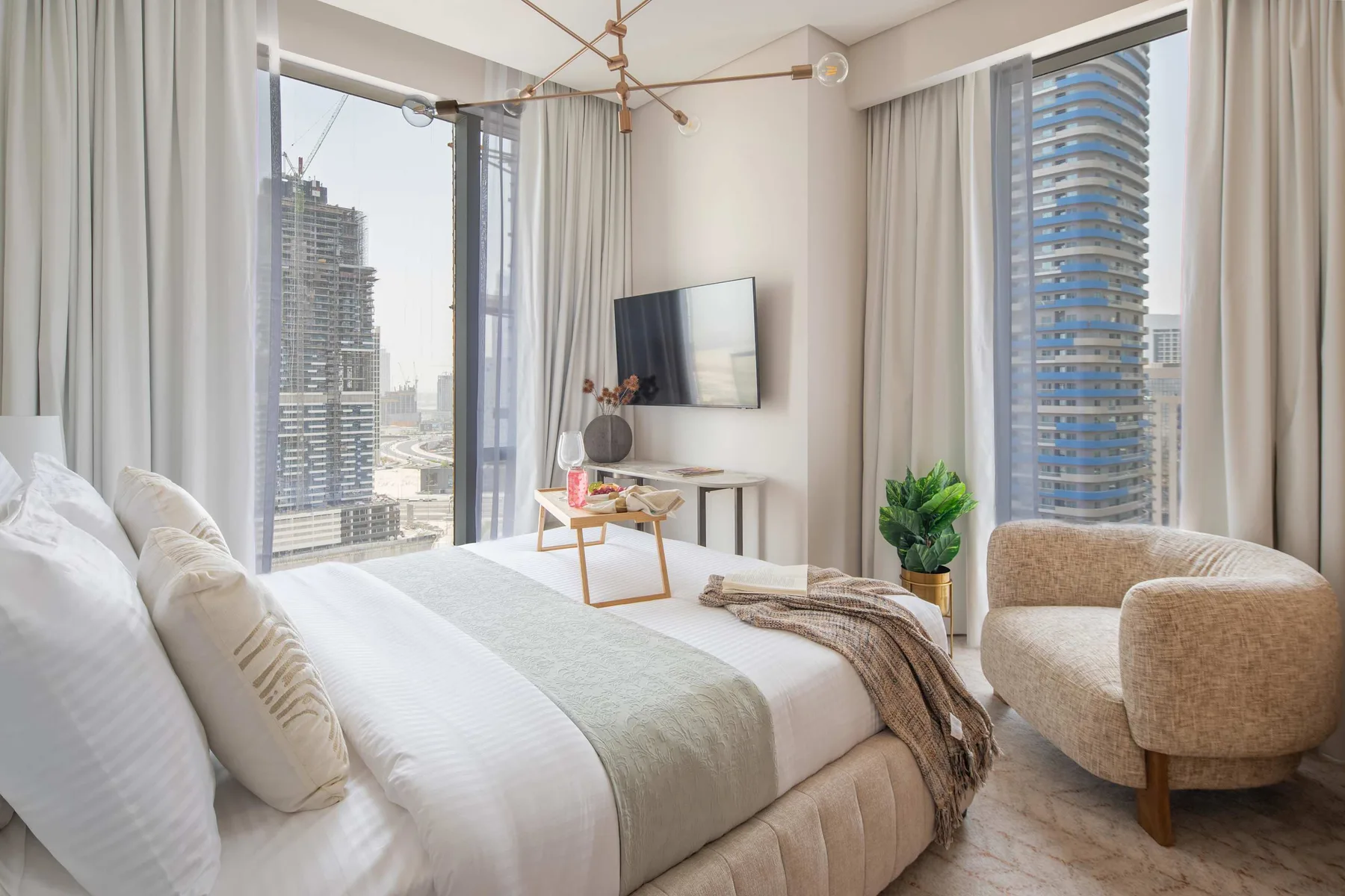 Un dormitorio luminoso con una cama grande, un sillón y ventanales.