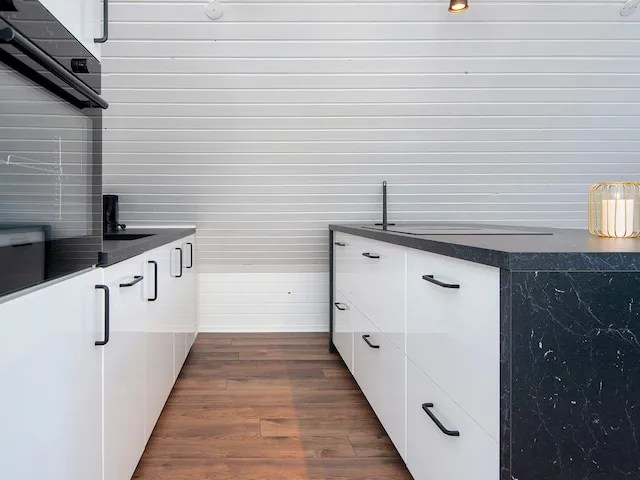 A modern kitchen with white cabinetry and dark countertops.