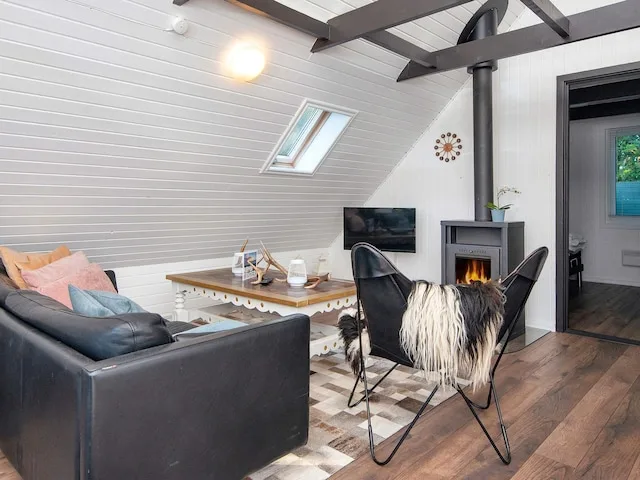 A living room with seating, a television, and a lit fireplace.