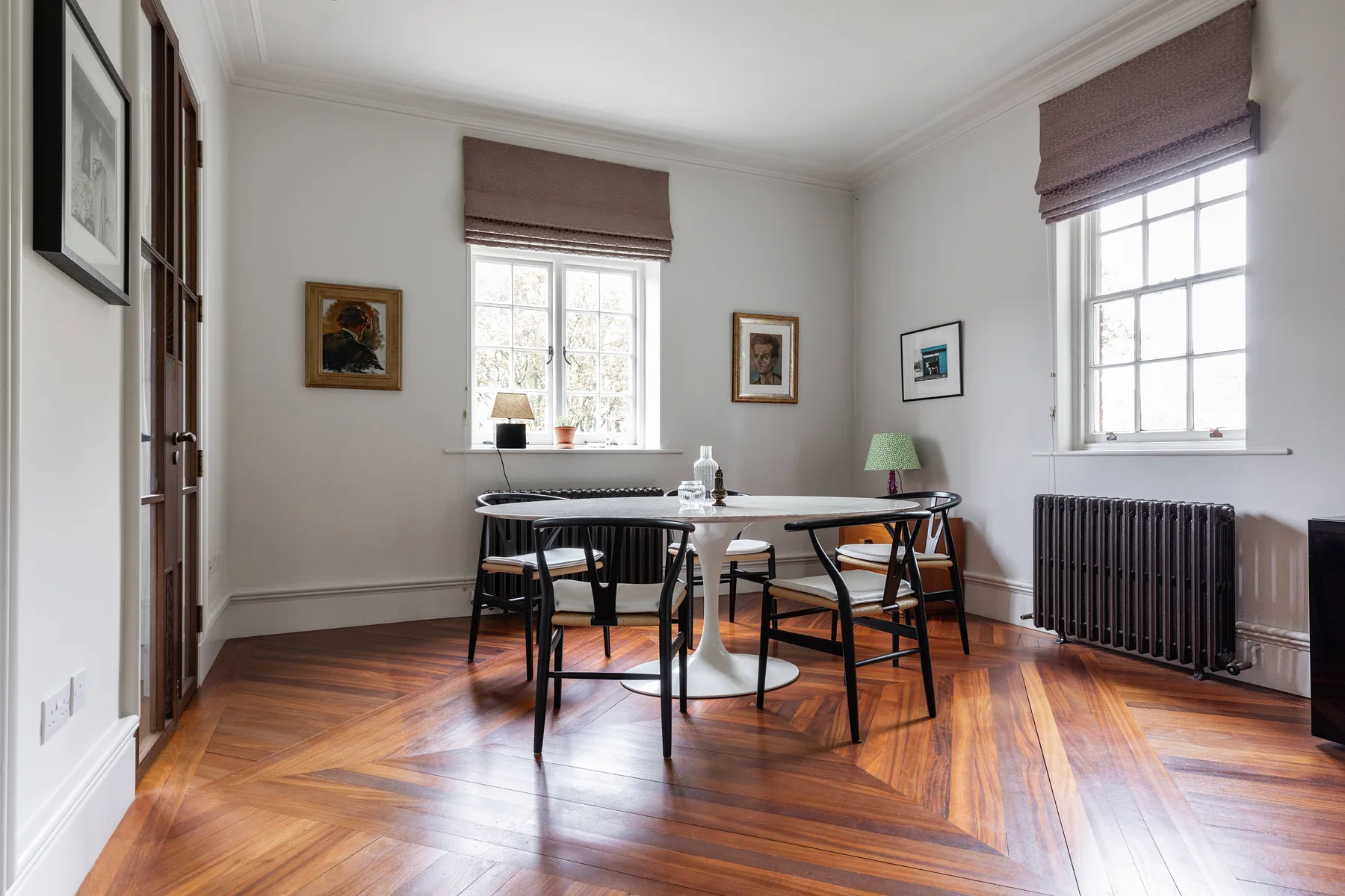 Un comedor luminoso con una mesa, sillas y ventanas grandes.