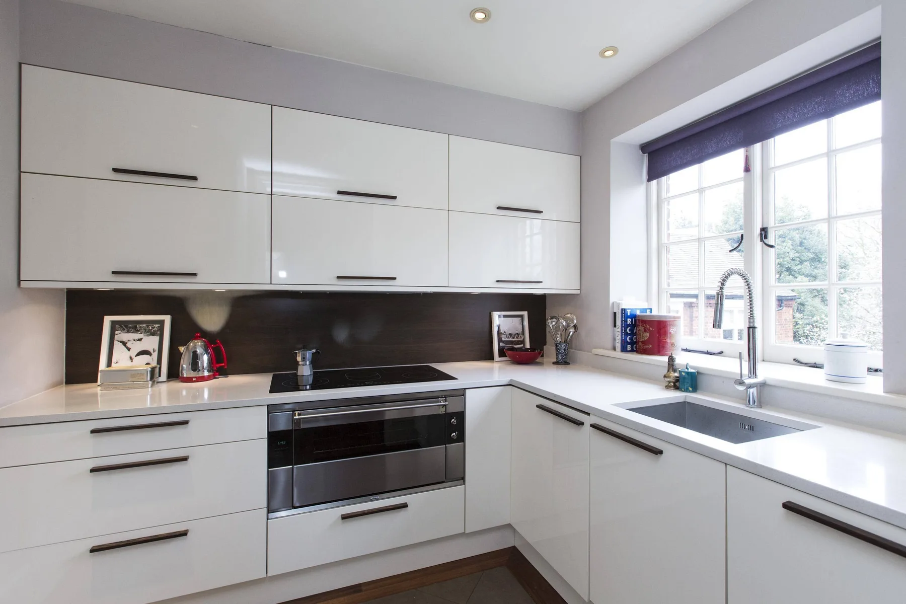 Una cocina moderna y luminosa con gabinetes blancos y una ventana grande.