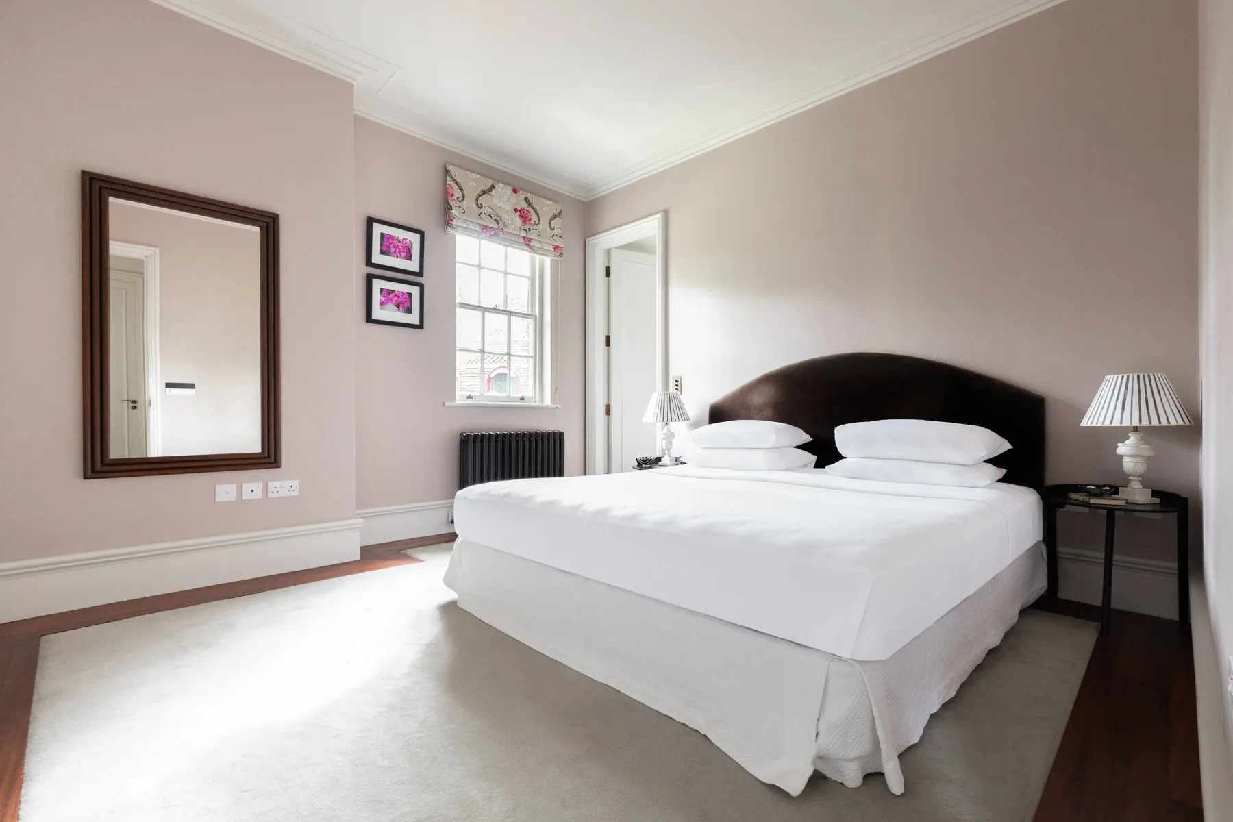 Un dormitorio luminoso con una cama bien tendida y una ventana.