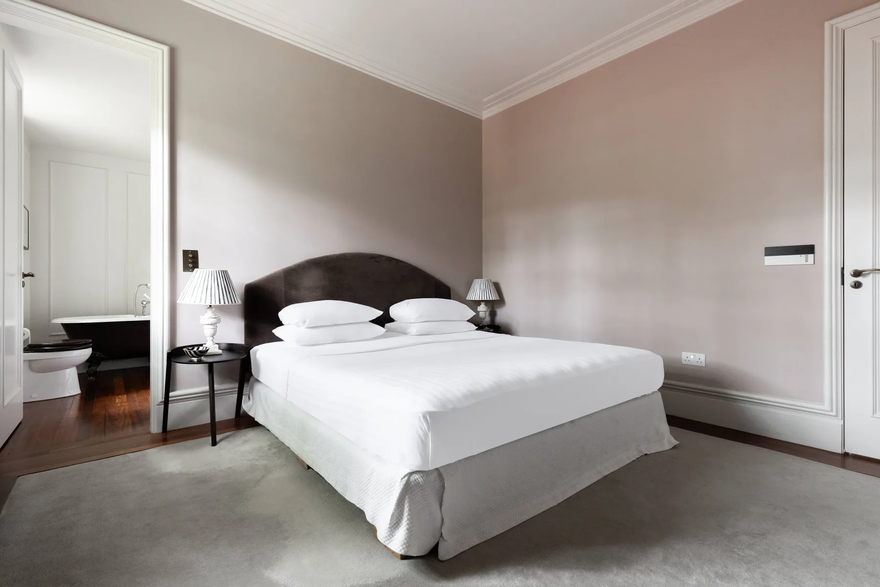 Un dormitorio con una cama vestida con ropa de cama blanca y mesitas de noche.
