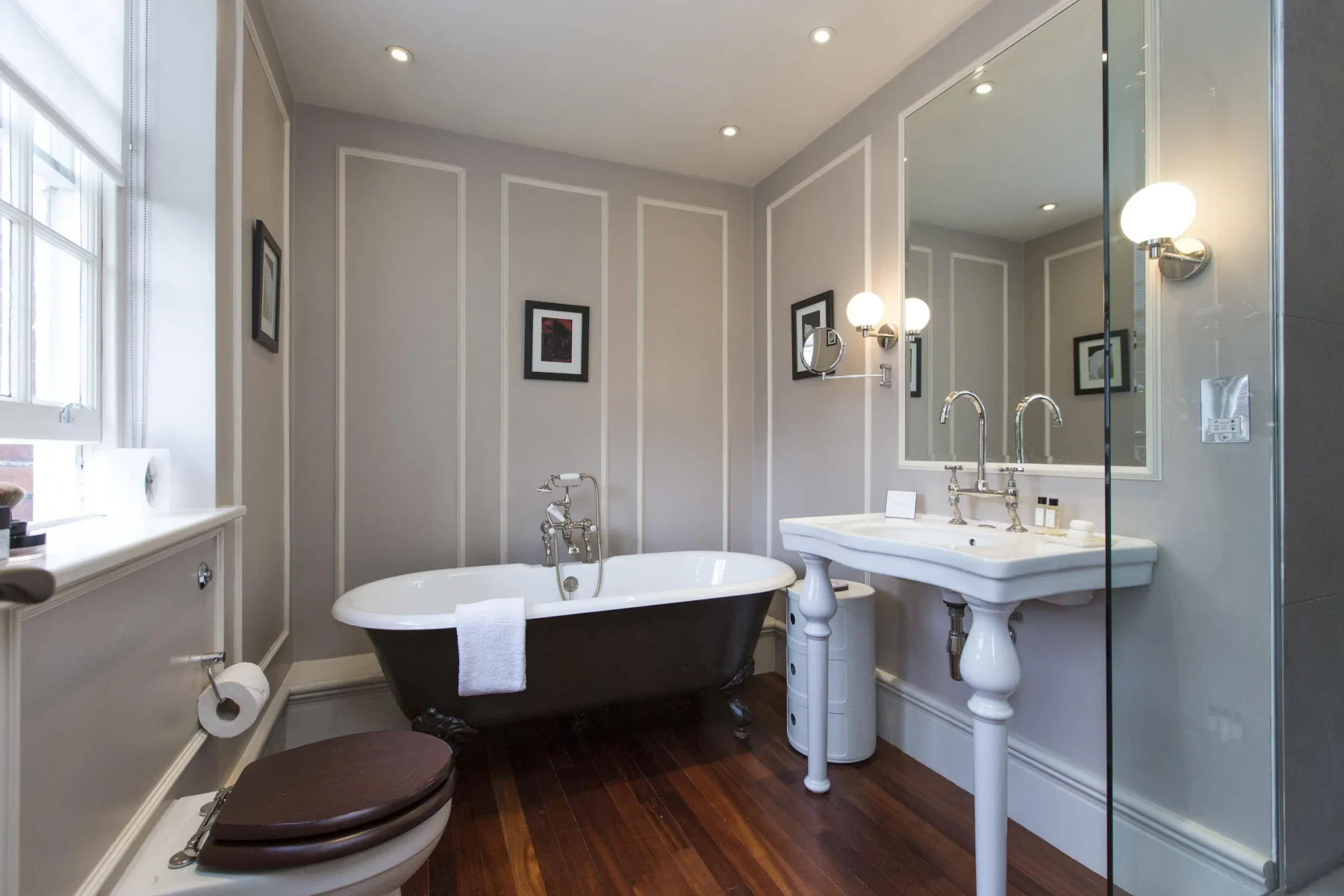 Un baño luminoso con bañera exenta, lavabos con pedestal y un espejo grande.