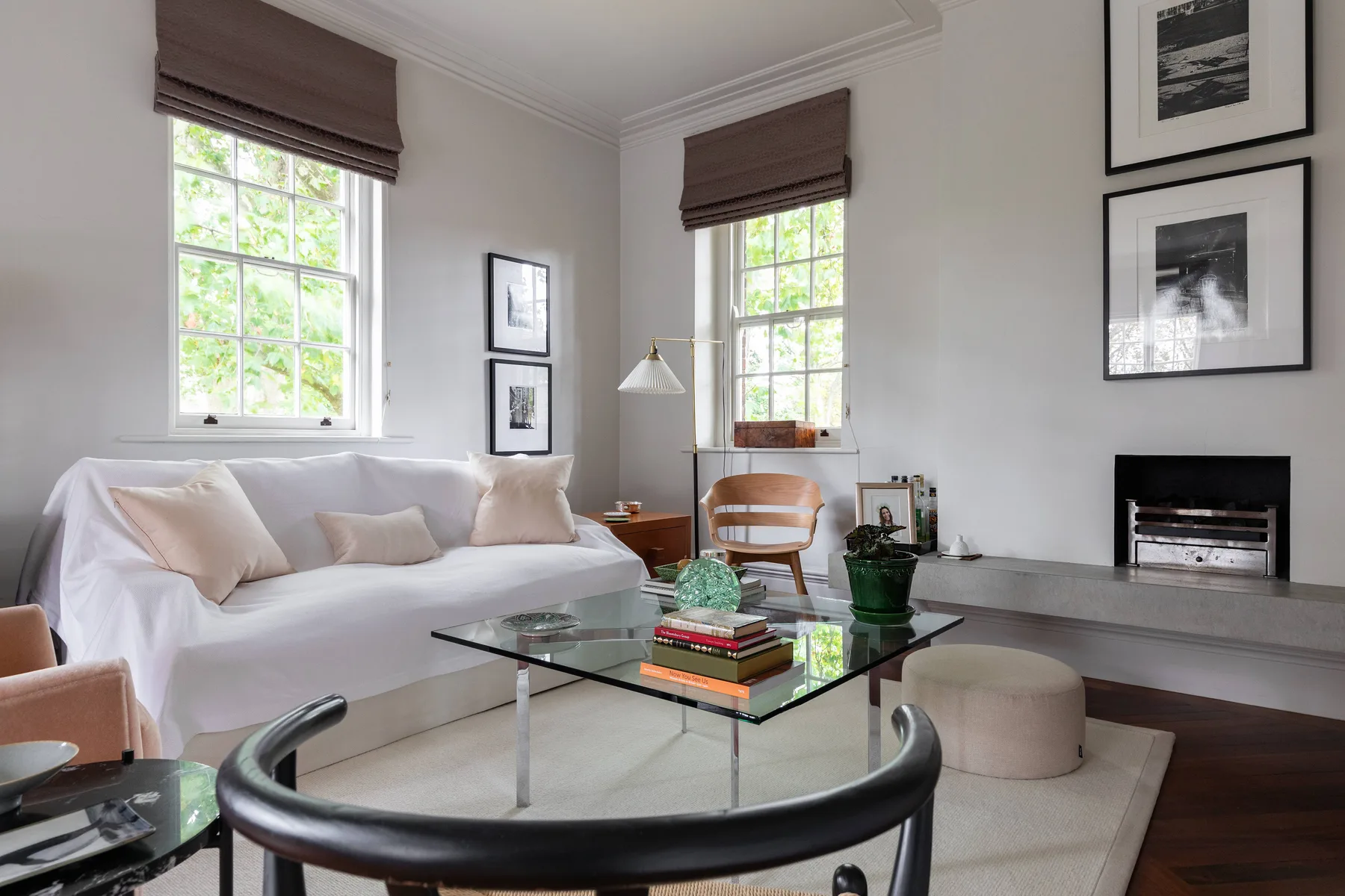 Una sala luminosa con asientos, una mesa de centro de vidrio y ventanas altas.