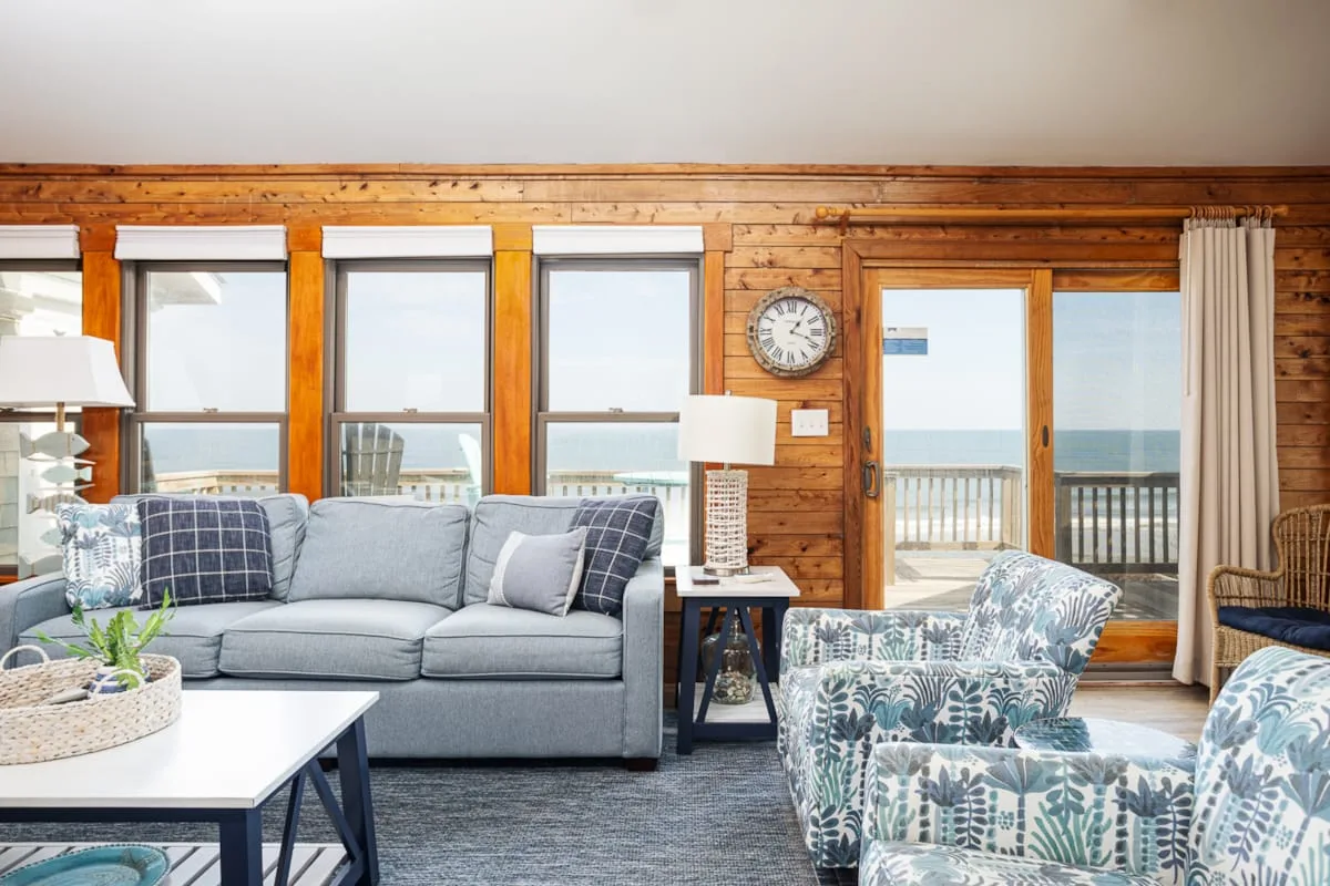 Una sala de estar con asientos junto a grandes ventanas con vista al agua.