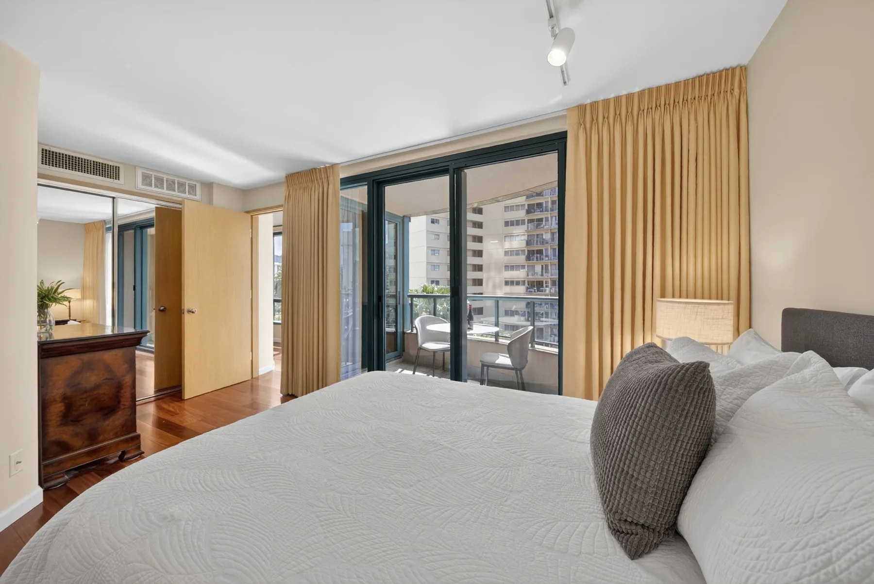 A bedroom with a bed facing glass doors and a balcony.