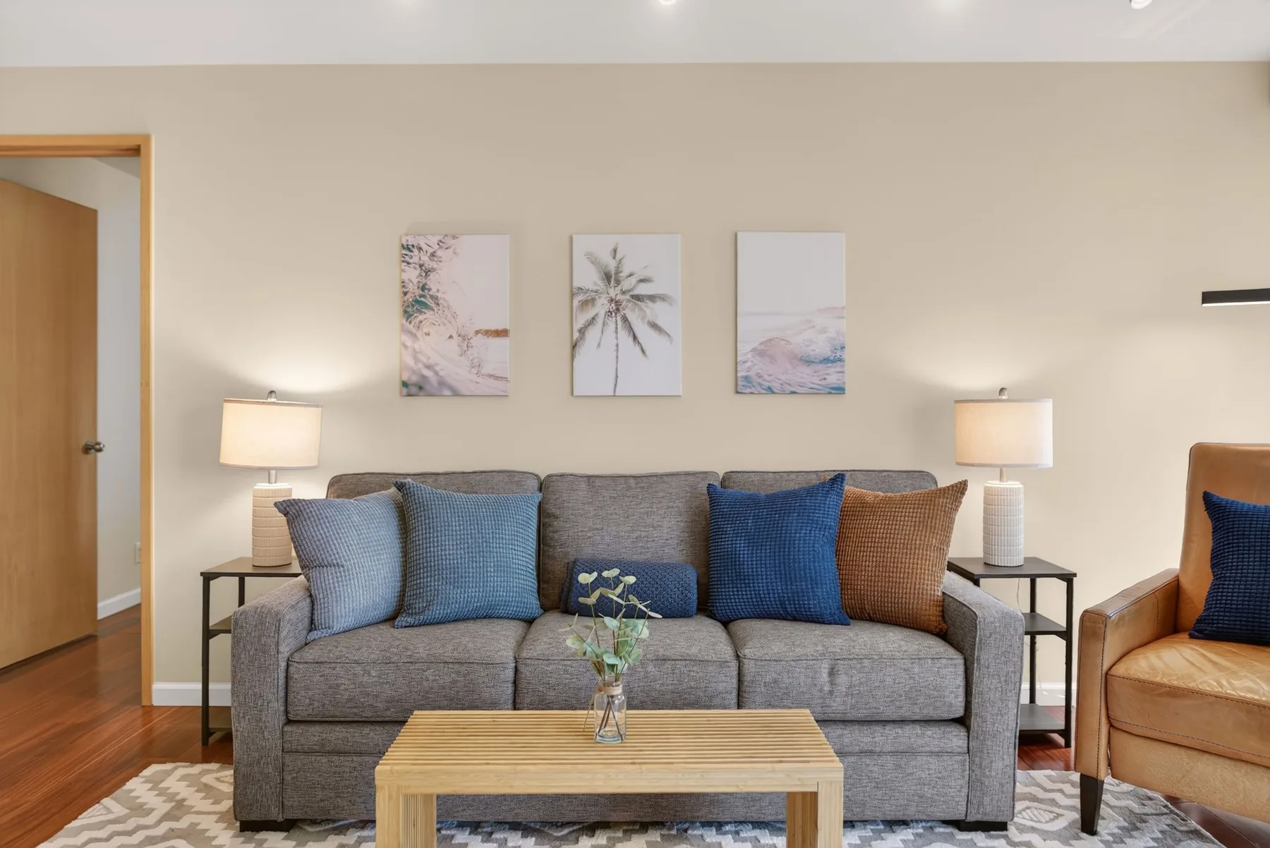 A living room with a gray sofa, wooden coffee table, and framed wall art.