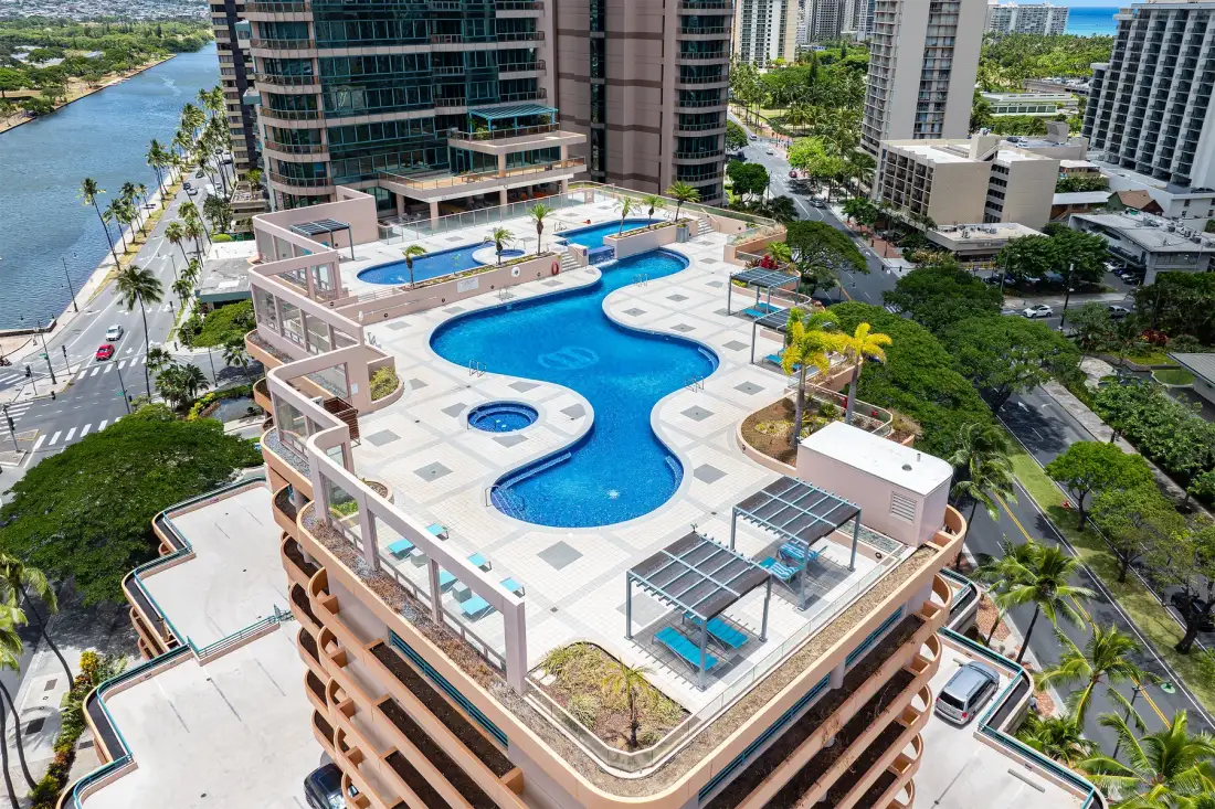 A rooftop pool deck with blue water and surrounding high-rise buildings.