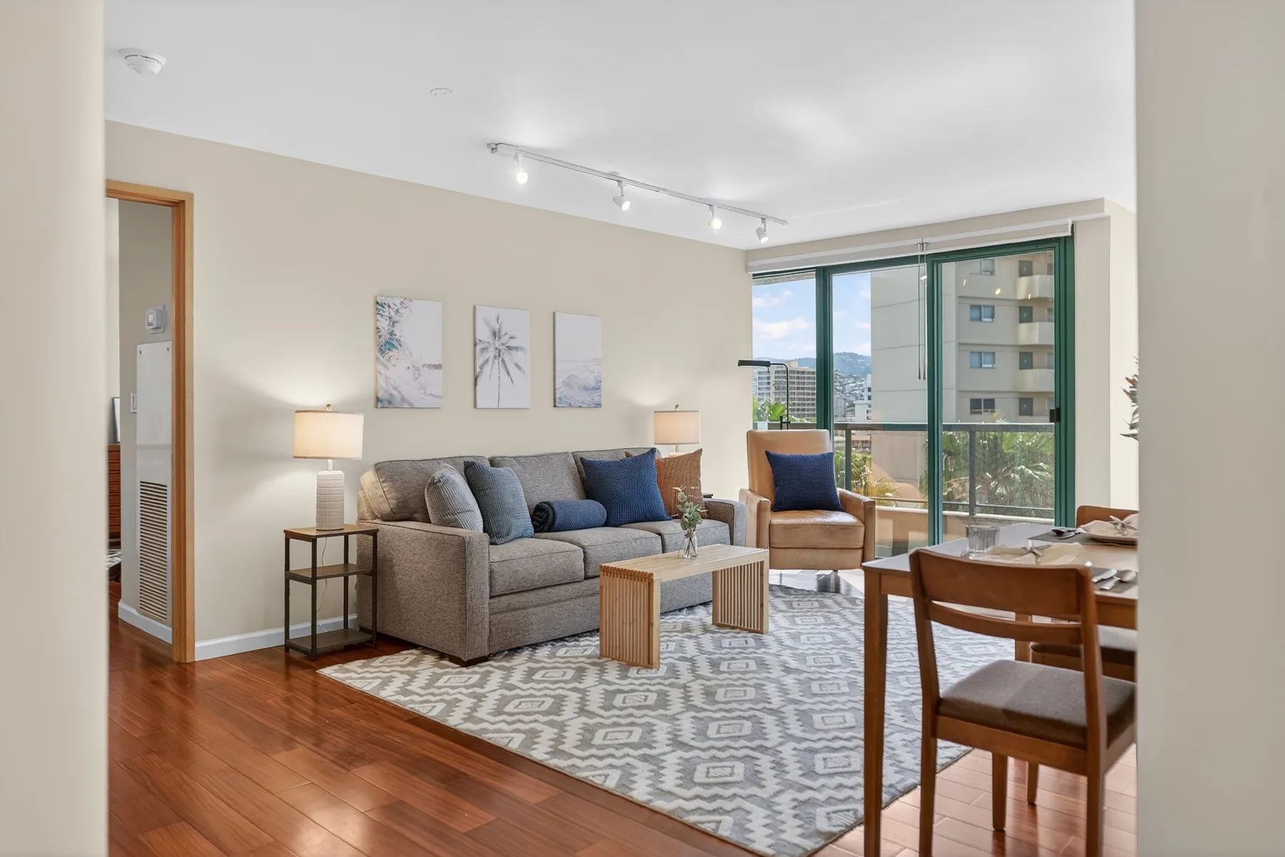 A living and dining area with seating, a rug, and large windows.