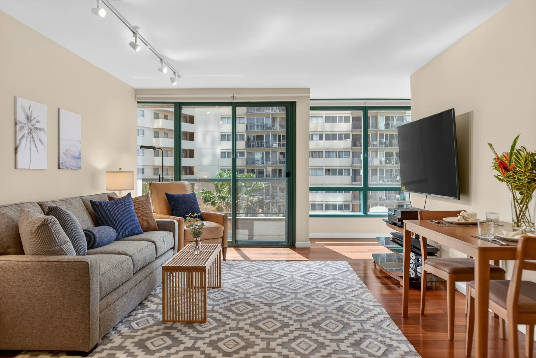 A living room with seating, a patterned rug, and large windows.