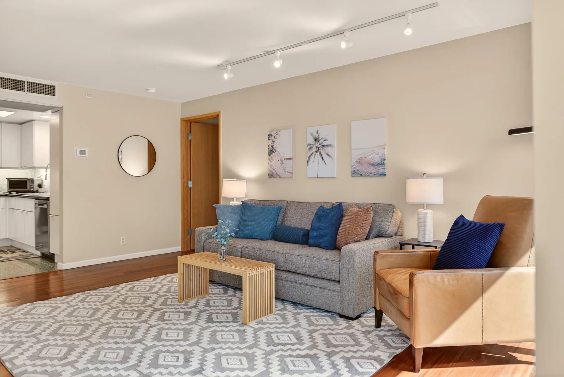 A living room with a gray sofa, blue cushions, and a patterned rug.