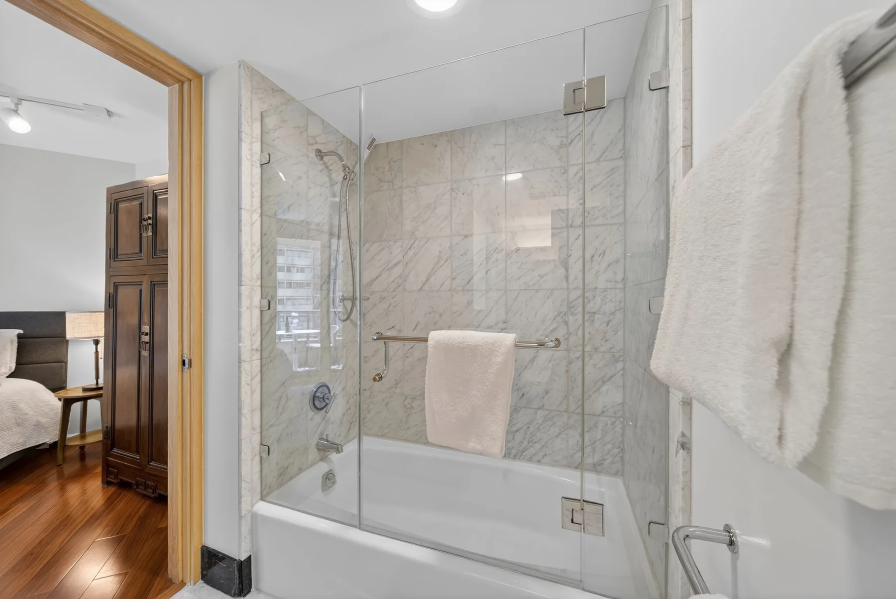 A bathroom with a glass shower and white bathtub.