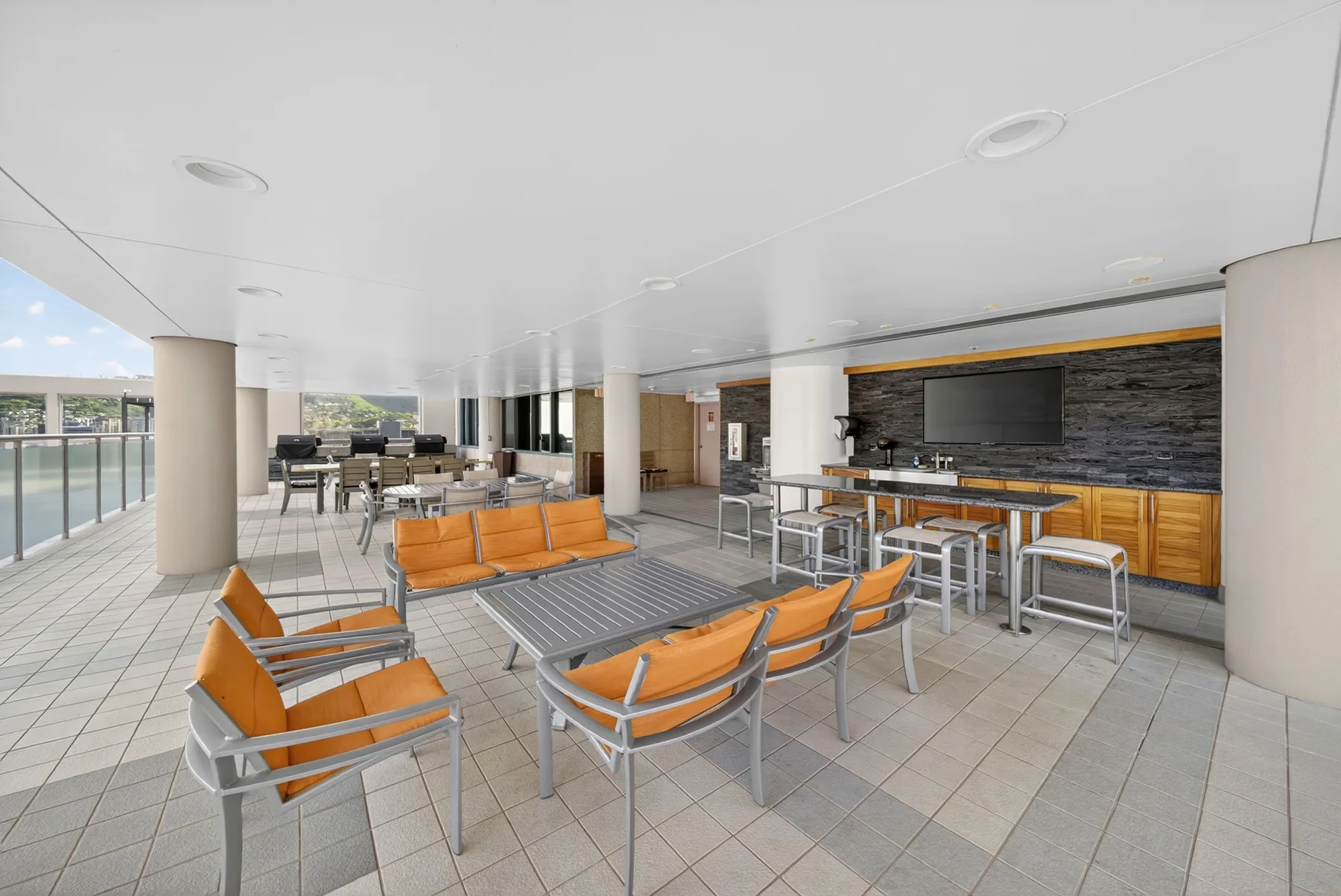 A covered patio lounge with orange seating and a long counter.
