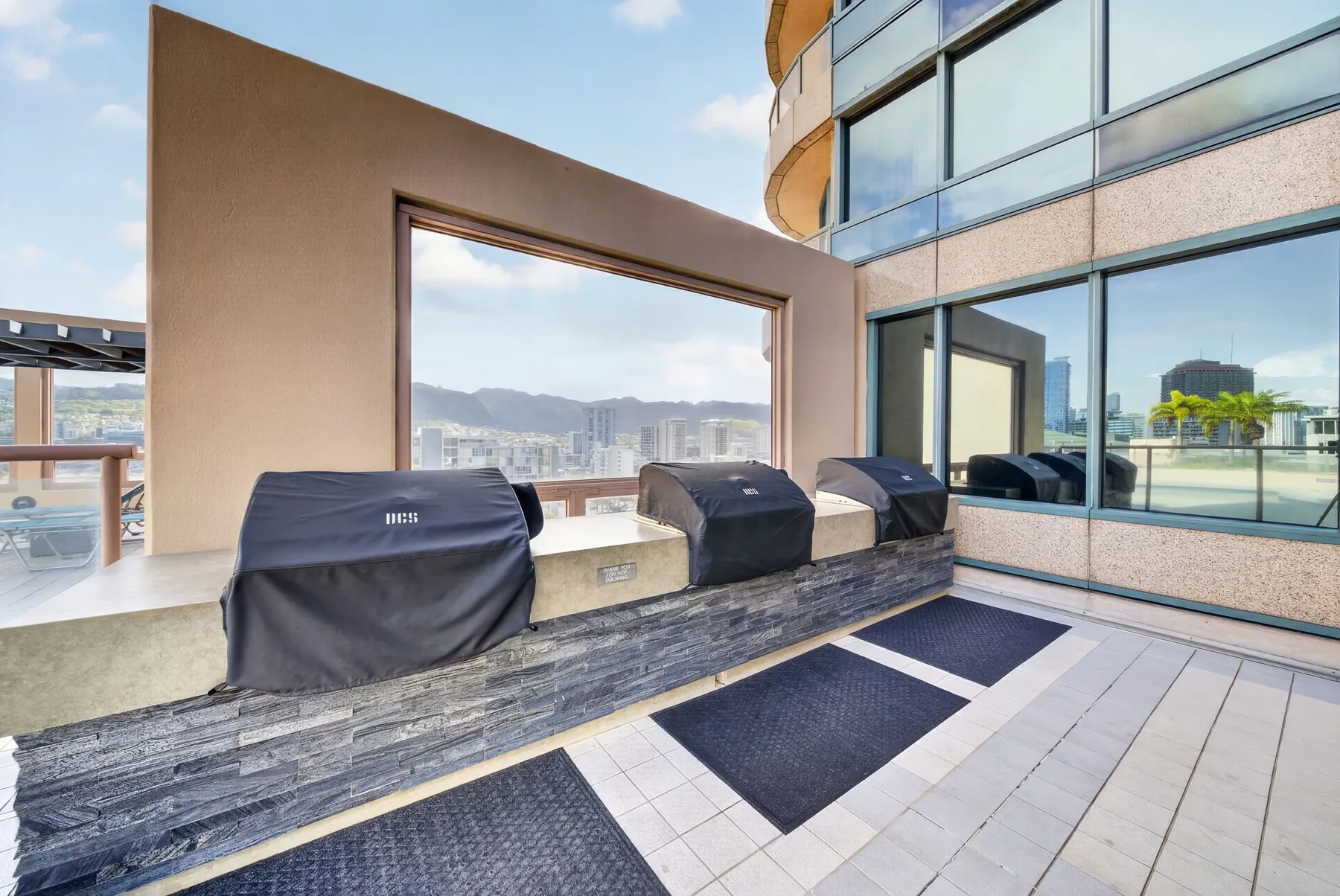 An outdoor seating area overlooks the city through a large open window.