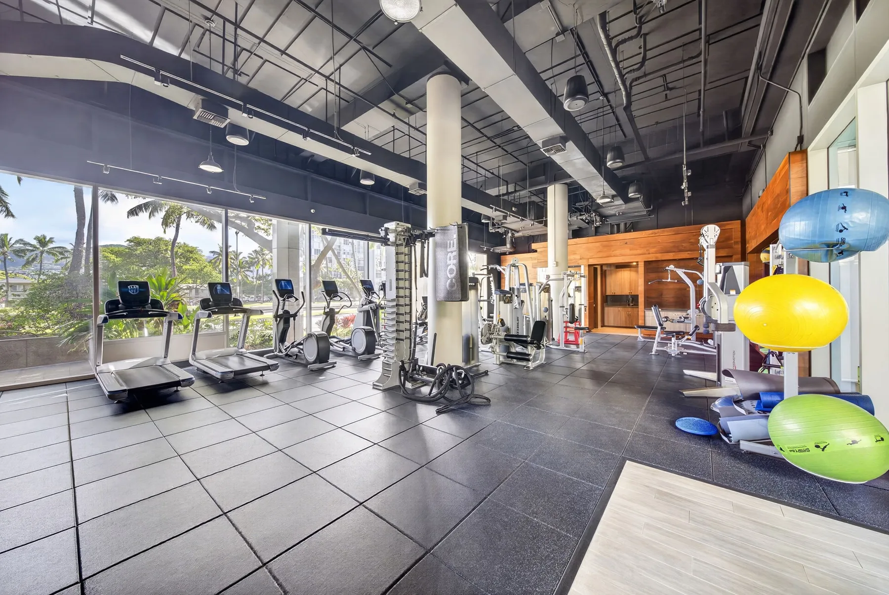 A gym with exercise machines, weights, and colorful fitness balls.