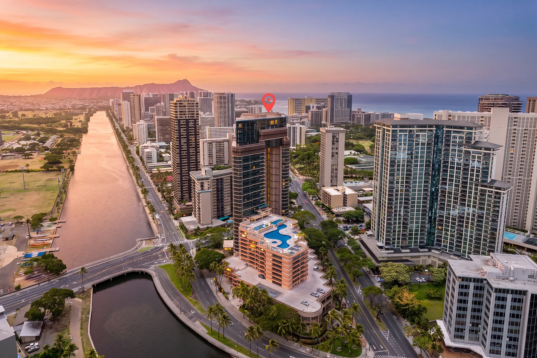 Aerial view of a coastal city skyline beside a canal at sunset.