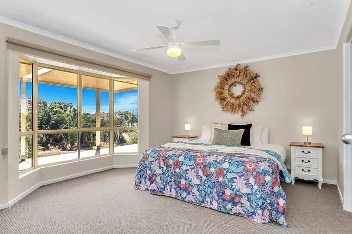 Un dormitorio con una cama bajo un adorno de pared y una ventana grande.
