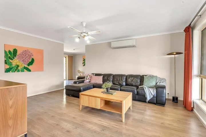 Una sala de estar con sofá seccional, mesa de centro y ventanas grandes.