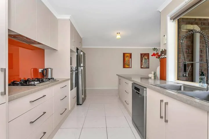 Una cocina luminosa con gabinetes claros, una encimera y un fregadero.