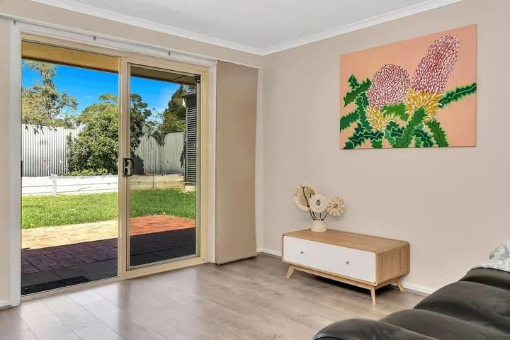 Una sala luminosa con puertas corredizas de vidrio que dan a un jardín.