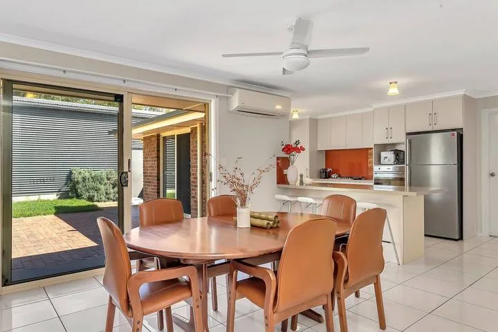 Comedor con una mesa y asientos junto a puertas corredizas de vidrio.