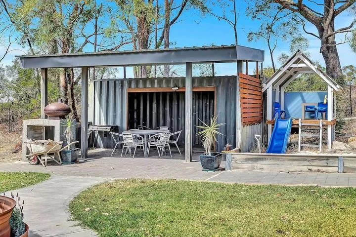 Un pabellón moderno al aire libre con asientos de patio está junto a un tobogán azul.